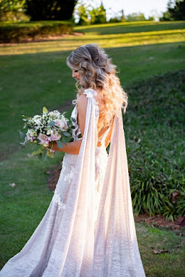 bride with two shoulder veils holding bouquet with curls in her hair