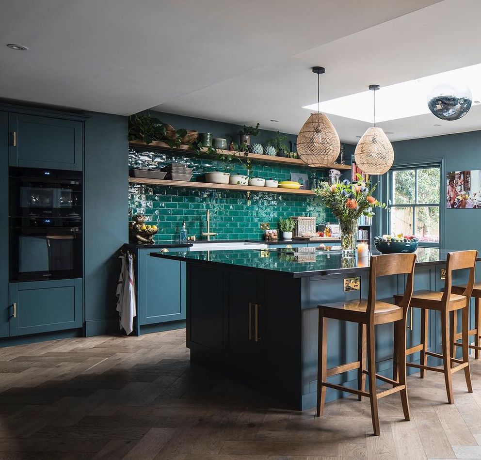Cucina con mobili grigio-blu piastrelle verdi e parquet