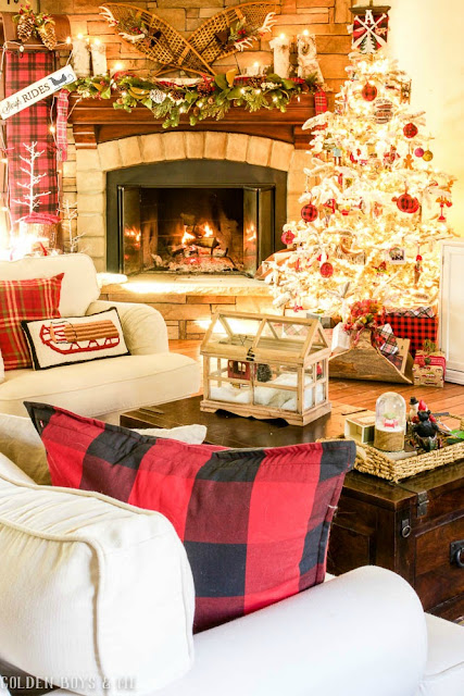 Cozy lodge style family room Christmas decor with stone fireplace, vintage snowshoes and toboggan