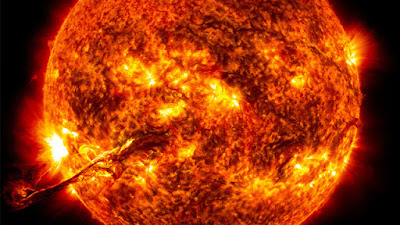   O Sol é a estrela mais próxima de nós. Todos os planetas do sistema solar giram ao seu redor e cada um com um período diferente. Ele é o responsável pelo suprimento de energia da maioria dos planetas. Quando as pessoas visitam observatórios as perguntas mais comuns que surgem a respeito do Sol são: o que é o Sol e como ele funciona? Do que ele é feito? Mas, antes de responder a essas perguntas veremos alguns dados curiosos a respeito do Sol.  O Sol só é uma estrela por causa da grande quantidade de massa que ele tem, 332 959 vezes a massa da Terra. Ele é constituído, principalmente dos gases hidrogênio e hélio, os dois gases mais leves que temos. Quando se diz que o Sol tem quase 98% de gases a pergunta mais comum que aparece é: como é possível o Sol ter tanta massa, ser tão grande sendo formado de gases?  Bem, essa é uma longa história e que nem mesmo os cientistas que estudam o Sol e outras estrelas sabem explicar exatamente como acontece, mas uma coisa eles sabem: Antes de existir o Sol e os planetas o que existia no lugar do sistema solar era uma enorme nuvem de gases e poeira muito maior que o sistema solar. Os gases são os que conhecemos: oxigênio, nitrogênio e principalmente hidrogênio e hélio; a poeira são todos os outros elementos químicos; ferro, ouro, urânio, etc... mas, a grande parte dessa nuvem era o hidrogênio e o hélio. Por algum motivo que ainda não é bem explicado essa nuvem encontrou condições para se aglomerar, se juntar em pequenos blocos, esses blocos começaram a se juntar em blocos cada vez maiores. Um desses blocos, o que se formou primeiro, no centro da nuvem, ficou tão grande e pesado que sua força gravitacional tornou-se suficiente para reter os gases com muita facilidade. Esse bloco aumentou tanto de tamanho e massa que acabou por se transformar numa estrela: o Sol. Os blocos menores que se formaram ao redor do bloco central deram origem aos planetas. CUIDADO! Muitas pessoas pensam que os planetas são pequenas bolhas expelidas pelo Sol. Isso porque os cientistas do século passado e começo deste século pensavam assim. Hoje em dia sabe-se que isso não é verdade. A teoria da nuvem de gás e poeira é a mais aceita entre cientistas atuais  LOCALIZAÇÃO  O Sol ocupa uma posição periférica na nossa Galáxia,ou seja, ele está a 33.000 anos luz do centro galáctico, o que corresponde a 2/3 do raio galáctico. Nós estamos num dos braços espirais, o braço de Orion, como mostra o esquema a seguir.   Figura 1: Localização do Sol na Galáxia  O Sol também está orbitando em relação ao centro gravitacional da nossa Galáxia. O ano do Sol é de aproximadamente 230 milhões de anos terrestres e sua velocidade orbital é de 250 km/s, sendo que todos os demais corpos do Sistema Solar o acompanham nessa viagem. Sabe-se que o Sol realizou cerca de 250 revoluções completas até hoje. A idade do Sol é de cerca de 4,5 bilhões de anos.    O Sol, estrela de quinta grandeza[1], é o principal componente do nosso Sistema Solar e o mesmo é um dos milhões de Sóis existentes em nossa Galáxia.  Se o Sol for colocado a distância de 32,6 anos-luz de nós, o seu brilho será semelhante ao de uma estrela de quinta magnitude. Objetos vistos ou comparados a essa distância, nós definimos o seu brilho como Magnitude Absoluta. O Sol tem magnitude absoluta igual a cinco, dai a expressão estrela de quinta grandeza.  CARACTERÍSTICAS GERAIS  Pela Lei da Gravitação Universal de Isaac Newton (1642-1727), foi possível obter a massa da nossa estrela que é estimada em 332 959 vezes a massa da Terra, equivalendo a 1,989 1030 kg, com um raio de 695 500 km . Sua densidade média é 1.4 g/cm3, mas a matéria não é homogênea em seu interior. A densidade no centro do Sol é muito maior, enquanto que nas camadas externas é muito inferior. O seu eixo de rotação tem uma inclinação em relação ao plano da eclíptica de 7° 15''.  Apesar de sua massa ser milhares de vezes maior que a da Terra, sua gravidade na superfície é apenas 28 vezes maior que a gravidade terrestre. A temperatura na sua superfície é de cerca de 5770 K, e não é uma superfície sólida, mas sim em estado de plasma e gás.  O fato de o Sol ser basicamente um corpo constituído por um fluido (plasma e gás), provoca o fenômeno conhecido como rotação diferenciada. A velocidade dessa rotação varia nas diferentes latitudes com um valor máximo no equador (2 km/s) correspondendo a 25,03 dias e uma mínima nos pólos com um período de 30 dias. Essas informações só foram possíveis graças às manchas solares, as quais nós abordaremos melhor mais adiante. Isso é a chamada rotação diferenciada, a qual nós representamos com o seguinte esquema.  Figura 2: Esquema da Rotação Diferenciada  O Sol representa 99,867% de toda a massa do Sistema Solar e a restante está dividida entre os planetas, asteroides, satélites, e cometas do Sistema Solar. A massa do Sol apresenta a seguinte distribuição:   Camadas Externas (Fotosfera e pouco abaixo) 0,2% de elementos pesados  7,8% de hélio  92% de hidrogênio  Tabela 1: Características Químicas.  Raio  695 500 km,  109 raios terrestres  Superfície  6,16 1013km2 11.881 vezes a terrestre  Volume  1,44 1018 km3 1,3 106 vezes o terrestre  Massa  1,9 1030 kg  334.672 vezes a terrestre  Densidade  1,4 g/cm3 0,26 vezes a terrestre  Luminosidade  3,9 1027 kW  --------- Temperatura Superficial  5770 K --------- Temperatura no Centro  1,5 107K --------- Gravidade Superficial  276 m/s2 28 vezes a terrestre  Tabela 2: Características Físicas do Sol.  O funcionamento do Sol e a sua Estrutura Interna  Quando só se conheciam as reações químicas (combustão) para a produção de fogo e calor, pensava-se que o Sol funcionava da mesma maneira, mas quando os astrônomos conseguiram calcular sua massa e quantidade de energia necessária para mantê-lo aquecido constatou-se que ele não iria durar mais de 100 anos. Como o Sol é muito mais velho que 100 anos, a natureza deveria ter criado outra maneira muito mais eficiente de se produzir energia. Só na primeira metade desse século é que se descobriu a existência da energia nuclear.  NÚCLEO: No Sol, a energia nuclear é produzida com o hidrogênio fazendo o papel de combustível. Sabendo como fazer a temperatura de um gás subir é possível entender como ocorrem as reações nucleares do Sol. Sabemos que, quando um gás é comprimido (pressionado) ele aquece. Perceber isso é fácil: encha um pneu de bicicleta usando uma bomba manual. O bico do pneu e a parte da bomba que está próxima do bico ficam bem aquecidos. Isso acontece porque o ar (gás) que está dentro da bomba é comprimido pela força que você faz. Quando o pneu fica quase cheio e você tem que fazer mais força, ou seja, comprime mais ainda o ar ele fica cada vez mais quente. Agora imagine no Sol onde a pressão é milhões de vezes maior que a pressão na Terra. Sabemos também que a pressão aumenta com a profundidade. Mergulhando numa piscina com 2 ou 3 metros já percebemos o aumento da pressão em nossos ouvidos. No Sol, pode-se afundar até 50 vezes o diâmetro da Terra sem chegar ao seu centro, fica até difícil de imaginar a pressão que existe lá. Toda essa pressão faz com que o hidrogênio atinja temperaturas de 15 milhões de graus no centro do Sol. Com o gás nessa temperatura e pressão é que ocorrem as reações nucleares que mantém o Sol aquecido. Essas reações são milhões de vezes mais poderosas que as reações nucleares produzidas na Terra. Além disso, não se conseguiu produzir, na Terra, reações do mesmo tipo que acontecem no Sol.   As reações nucleares do Sol transformam o hidrogênio em hélio e nessa transformação é liberada uma enorme quantidade de energia. Nós aqui na Terra recebemos uma pequenina parte da energia que o Sol produz.   Somente no século XX é que se atingiu conhecimentos teóricos suficientes para elaborar uma teoria a respeito de toda a energia que o Sol irradia . Sabe-se que o Sol está atualmente em equilíbrio térmico (temperatura média aproximadamente constante), mas nós sabemos também que ele emite muita energia na forma de calor e luz. Porém para se manter esse equilíbrio é necessário uma fonte interna de energia. Essa fonte está no seu núcleo, que através de reações termonucleares funde átomos de hidrogênio e forma átomos de hélio. Seu núcleo está a uma temperatura de 15 milhões de Kelvin e possui uma pressão da ordem de bilhões de atmosferas, sendo que esses valores vão decrescendo juntamente com a densidade, de modo não linear, conforme afasta-se do núcleo em direção à superfície. A variação térmica (considerada do núcleo para as camadas mais externas) determina a estrutura interna da estrela conforme o modo de propagação da energia. Os principais mecanismos de transporte energético encontrados no Sol são o radiativo e o convectivo, esquematizados a seguir:  O RADIATIVO: representado pela "Zona de Radiação'', é a camada do Sol onde a energia propaga-se da mesma maneira que a luz, ou seja, através da radiação e por isso não depende do meio para se propagar. O meio atua no sentido de atenuar a energia.  O CONVECTIVO: representado pela "Zona de Convecção'', é a camada do Sol onde a energia se propaga através de movimentos convectivos, ou seja, a parte que está em contato com a "Zona de Radiação'' é aquecida e, com isso, sua densidade diminui e tende a subir para a superfície e o que está na superfície desce para entrar em contato com a "Zona de Irradiação''. Esse é o mesmo processo que ocorre com a água fervente num recipiente em aquecimento no seu fundo.  Utilizando-se desse processo, o Sol está emitindo energia desde sua ignição a 4,5 bilhões de anos e os cálculos realizados indicam que ele emitirá energia da mesma forma por pelo menos mais 5 bilhões de anos, que é quando estarão esgotadas as reservas de hidrogênio em seu núcleo. É importante saber que a emissão de energia do Sol não é uniforme, ou seja, há variações no fluxo de energia emitida, que pode chegar, em casos excepcionais, a 5% do fluxo médio de energia. Atribuindo-se o nome de "Sol calmo'' quando ele mantem-se no mínimo de emissão de energia e "Sol ativo'' quando está no máximo de emissão. Esse mínimo ou máximo é observado quando há um número menor ou maior de fenômenos em todas as suas camadas. Essas variações influenciam o meio interplanetário, sendo que na Terra observa-se muitos efeitos na atmosfera e no campo magnético.  Figura 3: Esquema da Estrutura do Sol    Figura 4: O Sol visto no Visível com um filtro neutro  CAMPOS MAGNÉTICOS  George Ellery Hale (1868-1938) foi quem detectou os campos magnéticos solares. Utilizando-se de um instrumento, o espectrógrafo de alta dispersão, ele descobriu que algumas linhas produzidas nas proximidades das manchas solares eram duplas e até mesmo triplas ou seja, no lugar de uma linha com certo comprimento de onda, via-se uma linha à direita e à esquerda daquele comprimento de onda e até mesmo a original e duas outras laterais. Esse fenômeno de duplicação de linhas é chamado de efeito Zeeman e ocorre quando a fonte emissora de luz está submetida a um campo magnético (nesse caso a fonte emissora é a mancha solar). Hale pôde calcular o campo nessa região que chega a 5000 Gauss e ainda conseguiu provar que o campo magnético geral, gerado pelo Sol, é da ordem de 1 a 2 Gauss. Esse campo magnético está dirigido de norte para sul, porém nas regiões onde se encontram os campos magnéticos intensos (1000 Gauss), estes estão dispostos, no sentido leste-oeste. O estado de plasma, que se encontra a matéria Solar, oferece pouca resistência à corrente elétrica o que faz com que toda a estrela se comporte como uma bobina elétrica.  Descobriu-se posteriormente que as linhas de força do campo magnético estão confinadas no plasma, ou seja,   comportam-se como se estivessem ligadas às particulas que o compõem e acompanham o fluxo de matéria. Com isso a rotação diferenciada acaba deformando essas linhas como se fossem tiras de borracha. As linhas do campo magnético sofrem um processo de condensação, até cada grupo assumir a forma espiralada. Daí encontram-se espirais ao longo de todos os meridianos e todas no sentido leste-oeste (sentido de rotação). A concentração dessas linhas equivale a maior intensidade dos campos magnéticos em relação a situação inicial, e como a rotação não é uniforme cada espiral pode ser esticada até formar um laço. Em certos momentos os laços se rompem e afloram na superfície. Nesse momento temos a formação das manchas solares.  ESTRUTURA EXTERNA DO SOL  FOTOSFERA: Aparentemente a olho nu e com instrumentos de baixa precisão a superfície solar é bastante uniforme. Na realidade ela é formada por pequenas estruturas hexagonais, os grânulos, de forma irregular e separadas por zonas mais escuras. Verificou-se posteriormente que essas estruturas são topos de colunas ascendentes de gás aquecido que ao se resfriarem descem pelas zonas escuras vizinhas decorrentes dos processos de convecção, que mistura o gás nas camadas inferiores à fotosfera. Estima-se que a diferença de temperatura entre os grânulos e as zonas escuras é de cerca de 1000 K.   Como o campo magnético é muito intenso em certas regiões (pelos efeitos explicados anteriormente) as linhas ficam quase perpendiculares à superficie e a matéria tende a se mover ao longo das linhas, nesse caso, a matéria fica "confinada'' a elas. Com isso há um bloqueio no movimento convectivo e o plasma desloca-se verticalmente, acompanhando as linhas e não horizontalmente para descer pelas zonas escuras. Então reduz-se a propagação do calor em certas áreas, que se tornam mais frias que as áreas circunvizinhas, emitindo pouca radiação. Isto é que caracteriza a mancha solar na fotosfera.  Constatou-se que o número de manchas solares sofre variações periódicas e essas variações estão ligadas ao "Sol calmo'' e ao "Sol ativo''. Partindo do "Sol calmo'' ,estágio de mínima atividade, observa-se que durante 4,6 anos há um aumento rápido das manchas atingindo um valor máximo. Após esse máximo transcorrem cerca de 6,4 anos onde se constata uma diminuição gradual nas manchas, atingindo novamente uma atividade mínima. No total entre um estágio de 4,6 anos de "Sol ativo'' e o outro estágio de 6,4 anos de "Sol calmo'' decorrem cerca de onze anos. Embora cada onze anos de atividade seja igual ao outro no seu aspecto visual, deve-se considerar que a polaridade magnética do Sol se inverte, ou seja, as  manchas que ocorreram no hemisfério norte durante o "Sol ativo'', irão ocorrer no hemisfério sul no estágio correspondente ("Sol ativo'') e vice-versa. Com isso nós temos um período completo vinte e dois anos de atividades solares, quando então o ciclo recomeça.  CROMOSFERA: É uma região externa à fotosfera. A temperatura na cromosfera se reduz a partir da fotosfera até atingir 500 km de altitude com 4000 K e, então há novamente um aumento até atingir 9000 K a altitude de 2000 km quando se inicia a coroa. A observação da cromosfera, por muito tempo só foi possível quando ocorriam eclipses totais que encobriam a luz fotosférica. Só há poucas décadas desenvolveu-se um instrumento , o coronógrafo, que simula o eclipse solar total, e nada mais é do que um telescópio preparado com filtros e obstáculos especiais que permitem somente a passagem da luz da cromosfera e coroa.  Ocorrem ainda as protuberâncias solares que se elevam da cromosfera para a coroa. Estas são visíveis sem instrumentos durante os eclipses solares totais, ou com o auxílio do coronógrafo. Essas protuberâncias podem ser eruptivas, de rápida duração, ou protuberâncias quiescentes que podem durar várias rotações solares. As protuberâncias possuem uma densidade muito superior à coroa circundante e temperatura de 10.000 a 20.000 K. Esses fenômenos são devido à assossiação de campos magnéticos que variam de 20 a 200 Gauss.  Quando as explosões que dão origem às protuberâncias ocorrem, e isso aparece principalmente nas proximidades das manchas solares na fotosfera, é que se percebe a influência do Sol sobre a atmosfera terrestre. Tal atividade pode interromper as comunicações a longa distâncias. Ocorre que partículas com muita energia são lançadas ao espaço e atingem a Terra provocando uma ionização da atmosfera terrestre. Em consequência, a ionosfera (camada atmosférica terrestre) deixa de refletir as ondas de rádio emitidas pelo Sol para o espaço e as ondas de rádio das emissoras de volta para a Terra, podendo interromper as comunicações a longa distância. Grande parte da radiação emitida pelo Sol atenua-se na nossa atmosfera, a qual atua como filtro bloqueando as radiações mais prejudiciais às formas de vida na superfície terrestre.  COROA: É a camada mais impressionante do Sol e a mais extensa delas (abrange praticamente todo o Sistema Solar). A densidade da matéria nessa camada é cerca de 10 milhões de vezes menor que na fotosfera e diminui conforme se afasta do Sol. Em condições normais também não pode ser vista, pois a sua emissão de luz é um milhão de vezes menor que a luz da fotosfera. Pode ser visualizada em eclipses solares totais e com o coronógrafo. A Coroa pode ser distinguida em três regiões: Coroa interna com expessura 1,3 raios solares a partir da cromosfera; Coroa intermediária que vai de 1,3 a 2,5 raios solares e a Coroa externa de 2,5 a 24 raios solares. Ao longo da translação terrestre, a Terra caminha imersa na coroa solar, e a radiação presente nela (advinda do Sol) bombardeia continuamente nosso planeta.   Figura 5: O Sol observado através do ultravioleta evidenciando uma protuberância. Para podermos imaginar o quanto essa reação nuclear é poderosa vamos fazer a seguinte comparação. Se o Sol fosse formado pelo combustível mais eficiente que se conhece, que é o combustível usado no ônibus espacial, e todo o Sol fosse queimado, ele duraria cerca de 100 anos. Sendo movido a energia nuclear apenas 1/3 do hidrogênio do Sol será consumido e mesmo assim os cientistas acreditam que ele irá funcionar por mais 5 bilhões de anos. Considerando que ele já tem quase 5 bilhões de anos, a vida do Sol será de aproximadamente 10 bilhões de anos, ou seja o Sol irá durar 100 milhões de vezes mais do que se fosse movido por energia química.