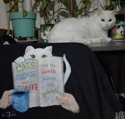 Betsy on my desk, next to my coffee mug. In front a t-shirt I painted with Betsy, a book and a coffee mug