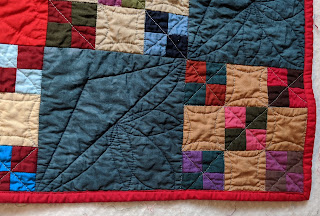 A darker red solid binds the Four-patch Nine-patch quilt