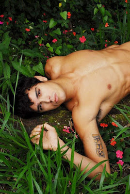 Brazilian male model Edilson Nascimento lying shirtless in the grass