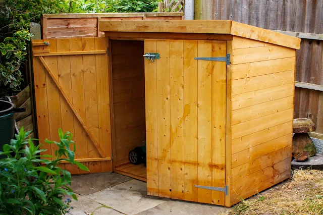 A small storage shed with the door open and a lawnmower inside