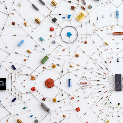 Technological Mandala, the work by Leonardo Ulian. A complex symetry pattern made from electronic components and microchips. It shows contrast between hard cold tech objects in a warm spiritual Hinduism symbol.