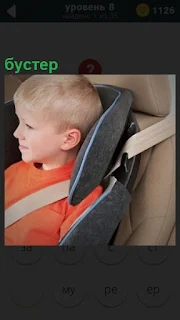 В авто кресле в автомобиле сидит ребенок,бустер его удерживает