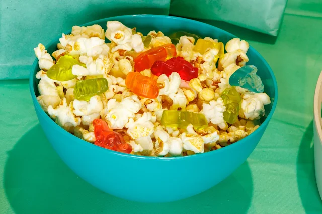 A close up of a bowl of popcorn with dinosaur jelly sweets in