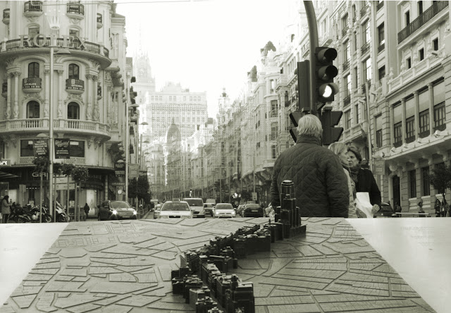 brązowa rzeźba prezentująca Gran Via z ulicą Gran Via w tle  