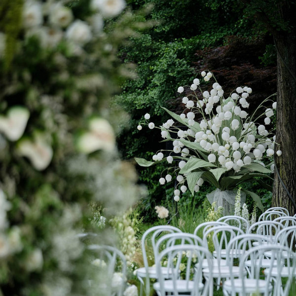 outdoor setting of large-scale lilies of the valley and white chairs placed in rows