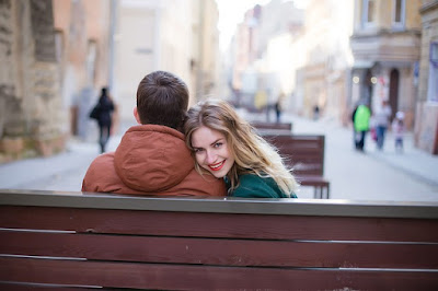 woman looks back at the camera with her head resting on a man