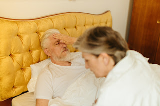 An elderly man sick in bed.