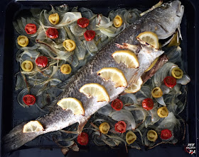 Corvina al horno con limón y guarnición de tomates cherrys y cebolla.