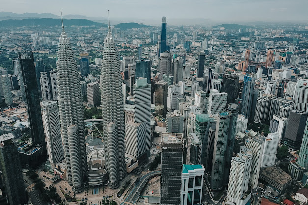 This is a panoramic view of the Kuala Lumpur city skyline, featuring the iconic Petronas Twin Towers, a landmark of Malaysia