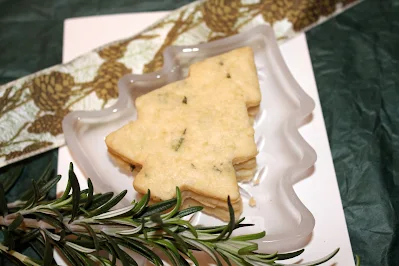 Stacked baked rosemary shortbread Christmas tree cookies on a small plate shaped like a Christmas tree.