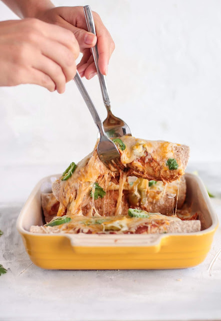 Enchiladas in a dish with one being lifted from the bowl