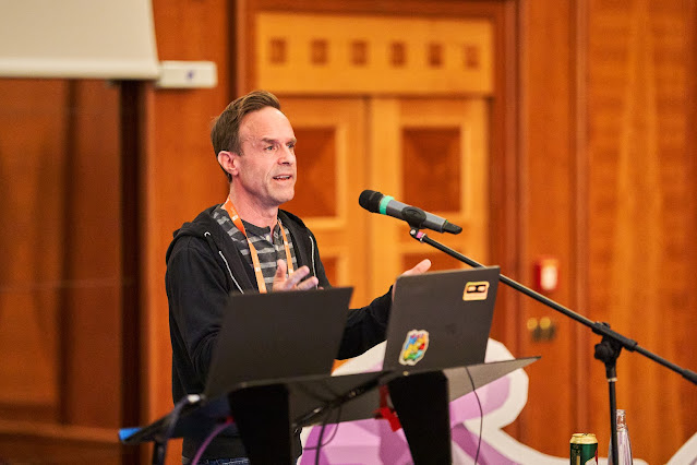 picture of a man at a microphone with a laptop on a podium