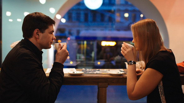 a couple sitting in a coffee shop sipping on coffee