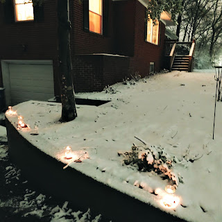 Candles on a wall in front of a house in snow