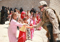 Lance Cpl. Gary A. Jacobs hands candy to little girls who wait with their mothers to be seen by a doctor during a Cooperative Medical Engagement in Fallujah, June 24.