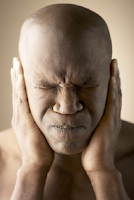 bald, African-American man with eyes and mouth closed tightly and his hands over his ears