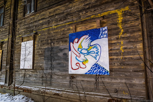 Картина с абстрактной птицей на стене деревянного дома