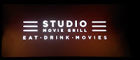 Picture of Studio Movie Grill's logo on a theater screen.