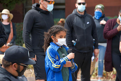 Young girl and community demonstrators in face masks