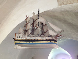 a model of a three-masted sailing ship hangs from a whitewashed arch