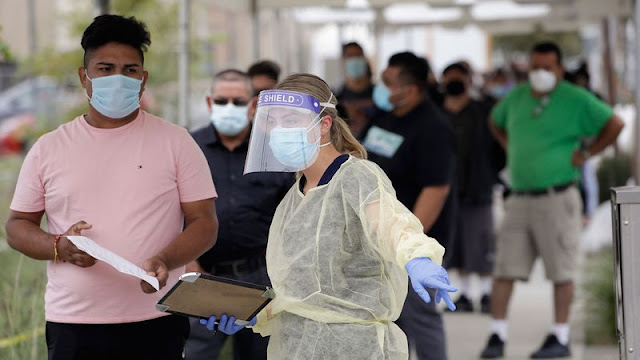People line up behind a health care worker at a mobile coronavirus testing site at the Charles Drew University of Medicine and Science in Los Angeles