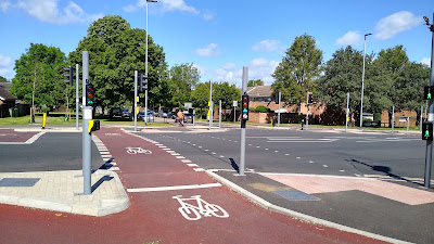 A red cycle track with a pair of mini traffic signals either side of a stop line for cycle traffic.