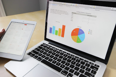 A Tablet besides a Computer diaplaying pie-charts.