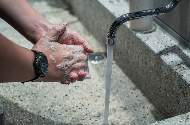 A person washes their hands with soap under a running tap.