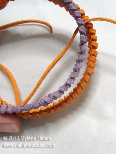 The woven orange bracelet has a larger diameter than the purple bracelet.