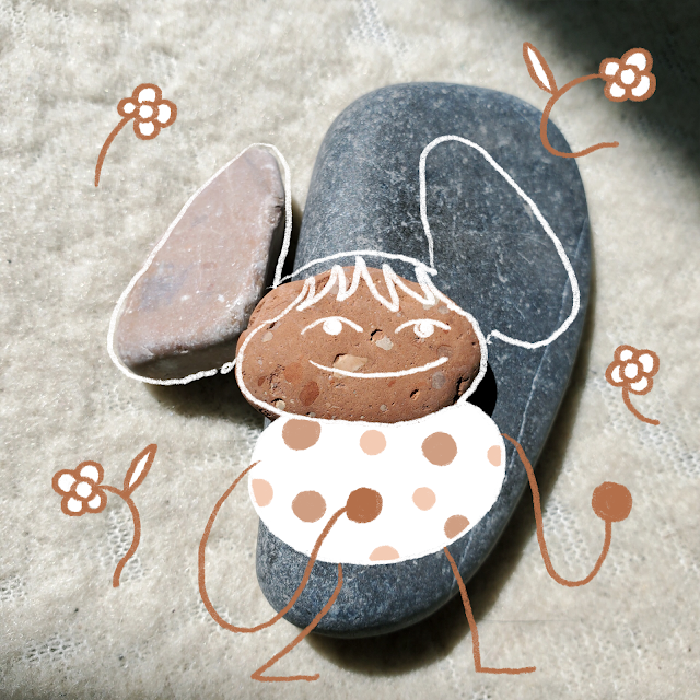 A person and flowers is drawn over a photo of three pebbles.