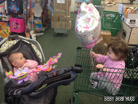 2 sisters one in a stroller and the other a shopping cart