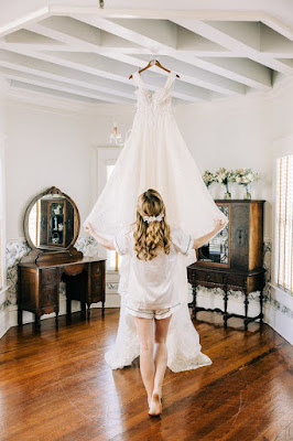 bride admiring wedding dress hanging from ceiling
