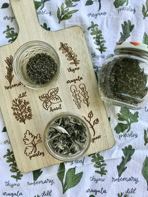 Jars of dried herbs including thyme, oregano, and sage.