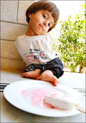 Ali eats watermelon with his feet at his parents' home in Amman