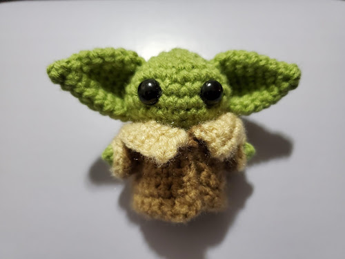 very small crochet baby yoda with large black eyes