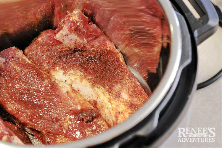 Seasoned Country Style Ribs inside inner metal pot of Instant Pot ready to cook