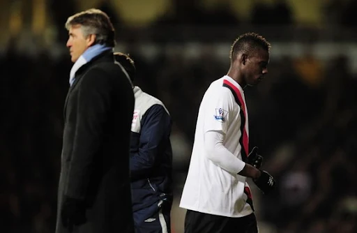 Mario Balotelli walks past his manager Roberto Mancini on the touchline as he is subsituted