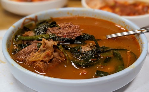 Goat, perilla, scallions, and stew served in individual bowl