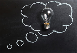 chalkboard with thought bubble drawn in chalk, surrounding an incandescent lightbulb