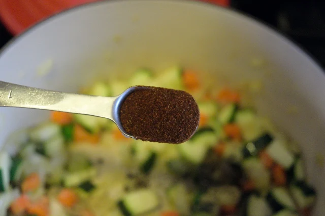 Chili powder being added to the pot. 