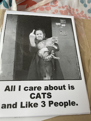 Card I bought of an old white lady in a babushka and dress on giving the middle finger to the camera while holding a cat in her arms with the saying: