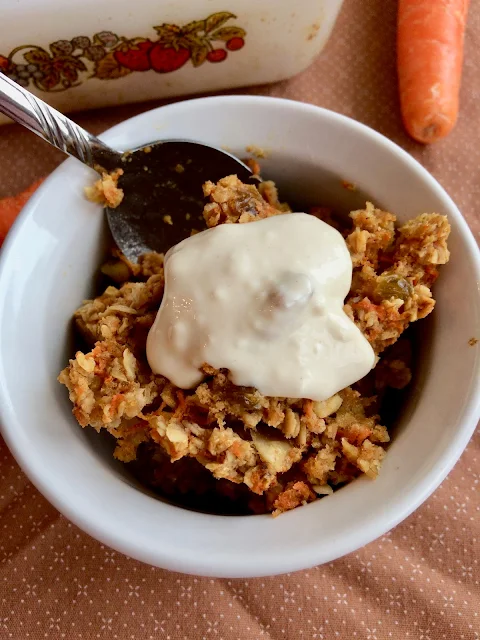 Close up of a bowl of baked carrot cake oatmeal with cream cheese topping.