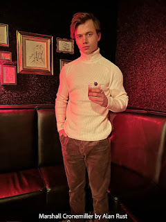 Marshall is at a cocktail bar wearing a cream turtleneck sweater