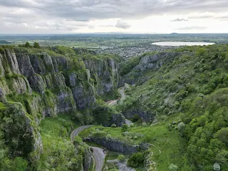 Lush green plants cover the craggy cliff faces of the Cheddar Gorge in Somerset, UK.