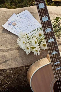 Foto de guitarra, partitura musical y flores