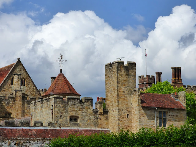 Blue sky and white cloud backdrop, with a skyline consisting of various turrets and chimneys of Penshurst Place in Kent